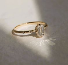 a diamond ring sitting on top of a white surface with sunlight coming through the window