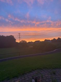 the sun is setting over a grassy field