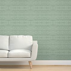 a white couch sitting in front of a wall with green stripes on the wall behind it