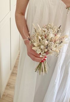 a woman in white dress holding a bouquet of flowers