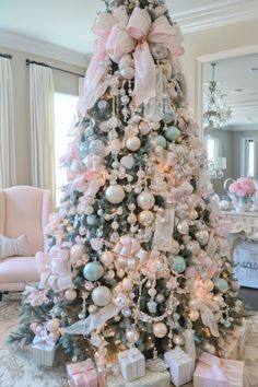 a white christmas tree with pink and blue ornaments, bows and presents on the top