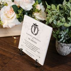 a wedding program is displayed on a table with flowers and potted plants in the background