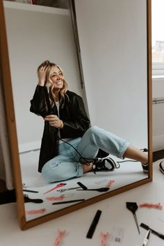 a woman sitting on the ground in front of a mirror