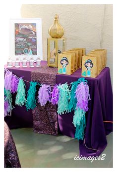 purple and green decorations on a table at a little mermaid birthday party