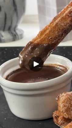 a person dipping chocolate into some kind of doughnut