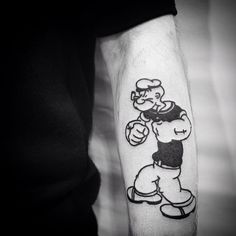 a black and white photo of a person with a cartoon character tattoo on his arm