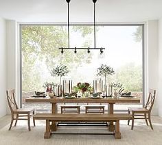 a dining room table and chairs in front of a large window with candles on it