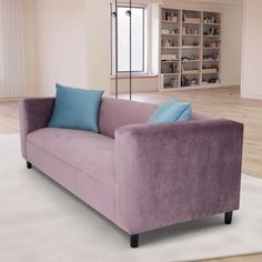 a purple couch sitting on top of a white rug in front of a book shelf