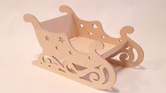 a wooden toy sleigh with stars and swirls on the sides, sitting on a white surface