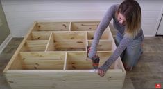 a woman is working on some drawers in the floor with a drill and screwdriver