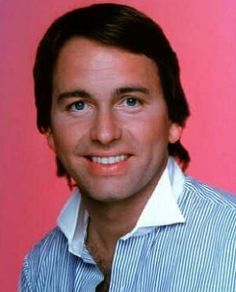 a man wearing a blue and white striped shirt with his hair in a pony tail