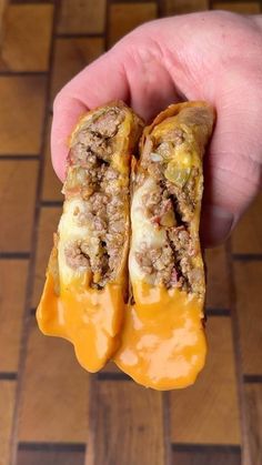 a hand holding two pieces of food in it's middle on a tiled floor