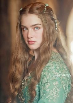 a young woman with long hair wearing a green dress and tiara, looking at the camera