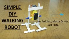 a toy robot sitting on top of a wooden floor next to a sign that says, simple diy walking robot