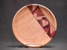 a wooden plate with an abstract design on the front and sides, against a black background