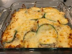 a casserole dish with zucchini, cheese and sauce on it in a glass pan