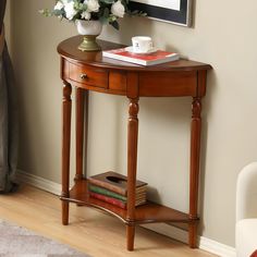 a wooden table with flowers and books on it in front of a painting hanging on the wall