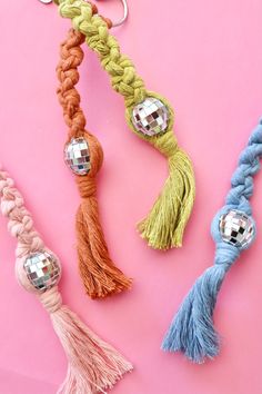 three different colored tassels are on a pink surface and one has a keychain