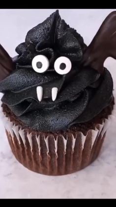 a cupcake decorated with black icing and spooky eyes