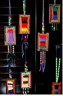 several colorful beads hanging from the ceiling in a room with black walls and wooden steps