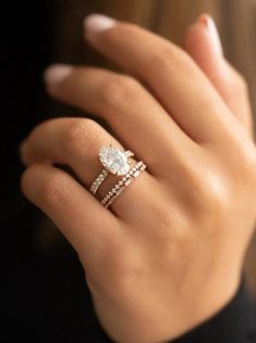 a woman's hand with a diamond ring on top of her finger and the other hand holding an engagement ring