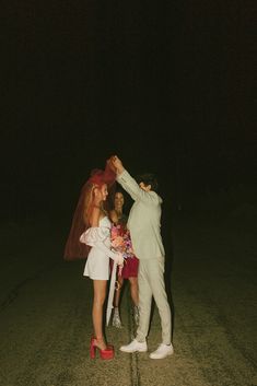 two people dressed up in costumes and one is holding the bride's veil over her head