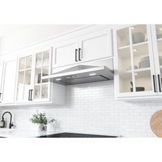 a kitchen with white cabinets and black counter tops is shown in this image, there are plates on the stove