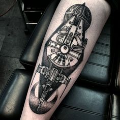 a tattoo on the leg of a person with a clock and wheel in black ink