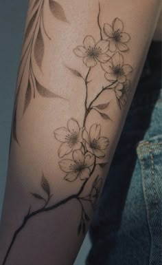 a woman's arm with flowers and leaves on it