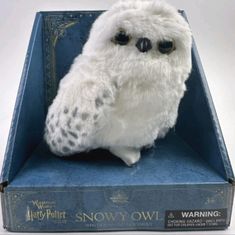 a white stuffed owl sitting in a blue box