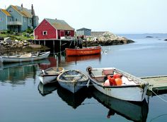 several small boats are docked in the water near some houses on stilts and rocks