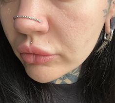 a close up of a person with piercings on their nose