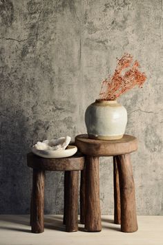 a white vase sitting on top of a wooden table next to two small stools