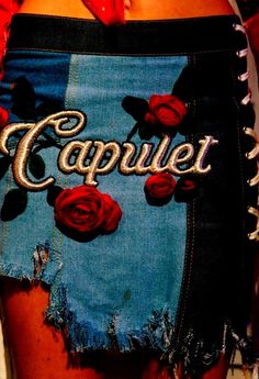 a woman's jean skirt with roses on it and the word capule written in white letters