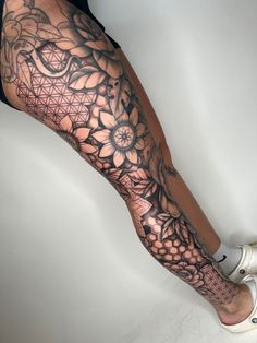 a woman's leg with tattoos and flowers on it