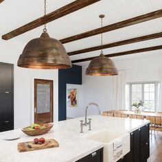 a kitchen with an island, sink and hanging lights