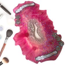 the contents of a pink and silver makeup set on a white surface with glitters