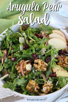 a salad with apples, walnuts and cranberries in a white bowl on a table