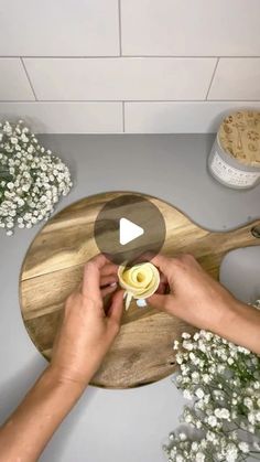 a person is holding a flower on a cutting board