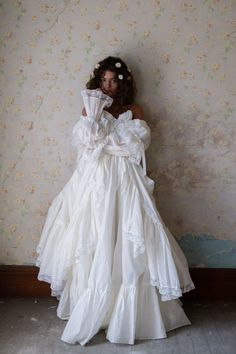 a woman in a white dress standing against a wall