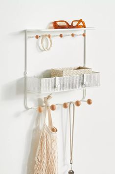 a pair of glasses hanging on a white wall next to a shelf with some tassels