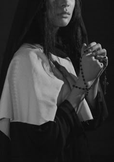 black and white photograph of a woman wearing a nun outfit holding a rosary in her hands