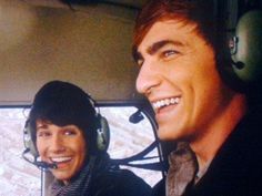 two men are smiling while sitting in the cockpit of an airplane with headsets on