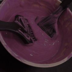 two brushes are in a bowl of pink dye