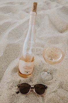 a bottle of wine and sunglasses on the sand