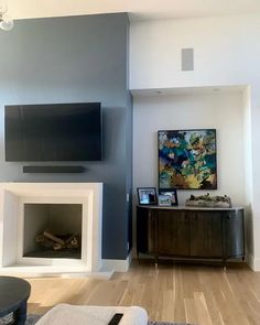 an empty living room with a fireplace and television on the wall, in front of a painting