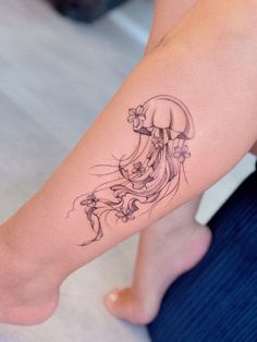 a woman's foot with a tattoo on it and a jellyfish in the background