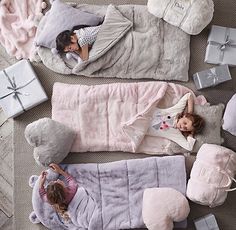 two small children laying in bed with stuffed animals and gifts on the floor next to them