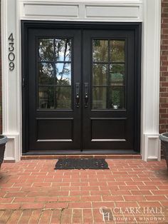 a black double door with two planters on either side