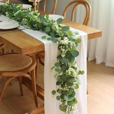 the table is set with greenery and place settings